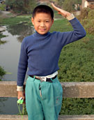 Young boy saluting by ancient Si Ben bridge, near Tongli